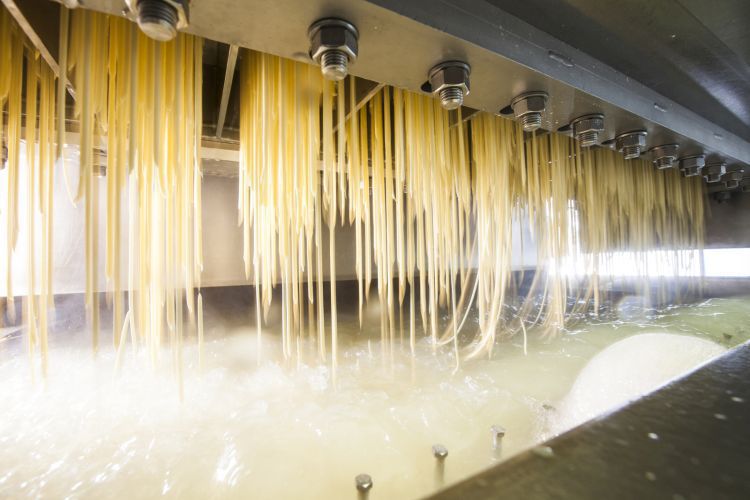 The dough is pressed through perforated plates and then drops into a cooking bath. Here, the Spätzle are briefly pre-cooked and thus retain their shape.